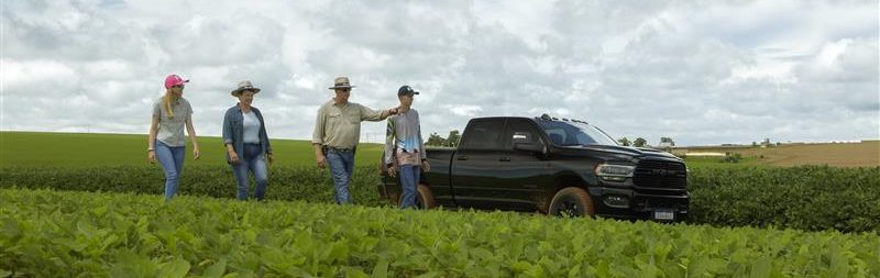 Produtores caminhando por uma lavoura ao lado de uma caminhonete durante vistoria no campo.